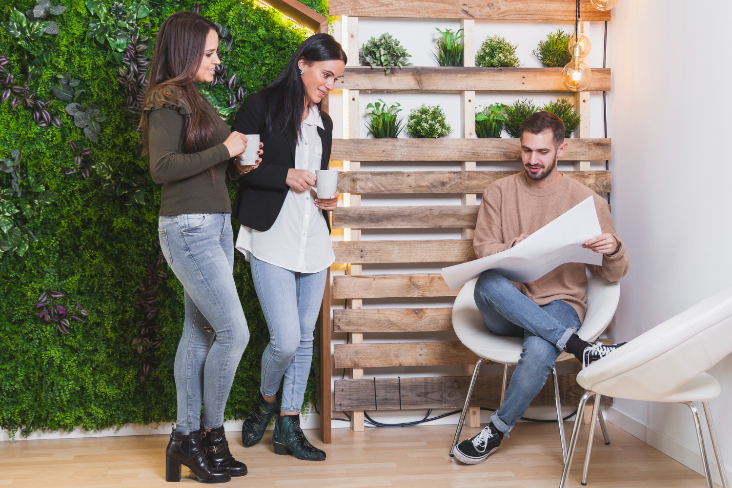 Three people pose in front of a plant-covered wall, showcasing a lively and green environment