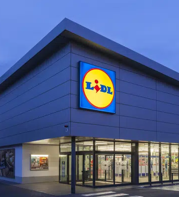 Exterior view of a Lidl supermarket at dusk with illuminated signage and modern architecture
