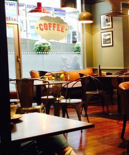 Cosy café interior with wooden floors, vintage decor, and warm lighting, featuring a barista station and seating areas