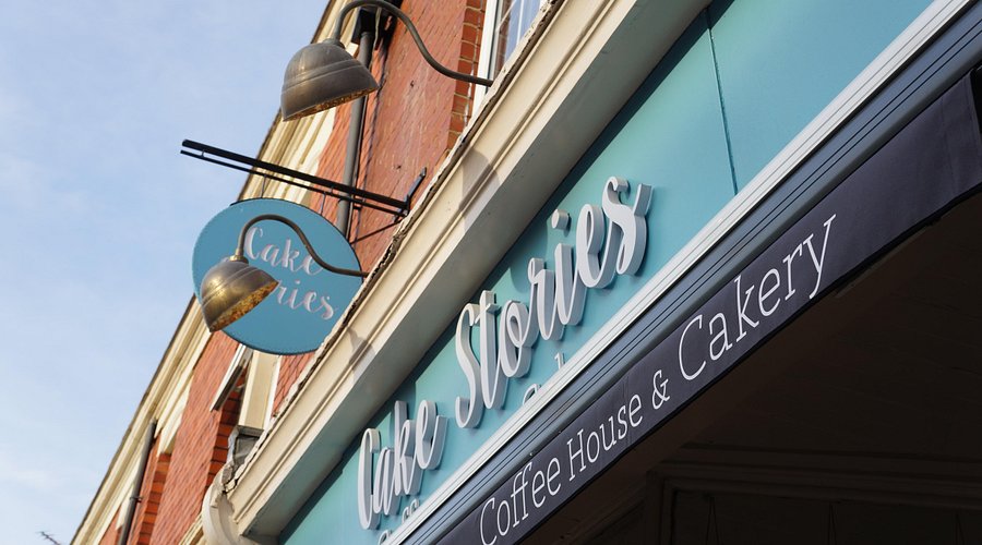 Vintage café exterior with Cake Stories sign on a blue awning in the UK, featuring traditional architectural details