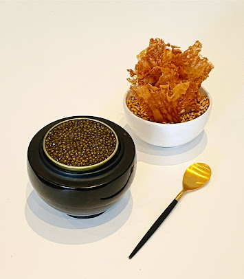 Luxury black caviar in a bowl with crispy crackers on the side and a golden spoon for serving