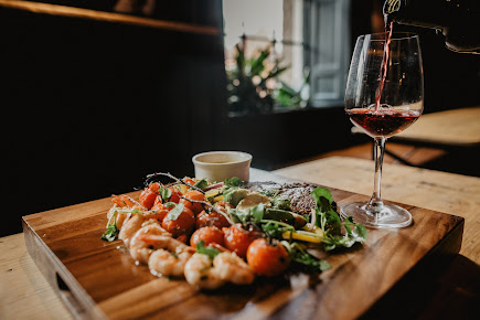 Gourmet seafood and salad platter with a glass of red wine being poured in a cosy restaurant setting