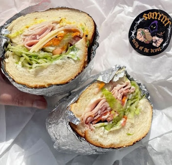 Delicious deli sandwich with ham, lettuce, and tomato wrapped in foil, perfect for a quick and tasty lunch