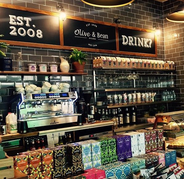 Cosy café interior with pastries, coffee machine, and tea selections at Olive & Bean, established in 2008