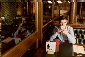 A man seated at a table with a steaming cup of coffee in front of him